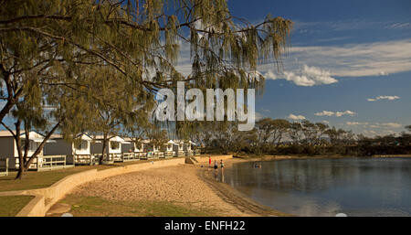 Vue panoramique de la maison de bord de plage, cabines, arbres et ciel bleu avec des gens dans une eau bleue du lac à Nambucca Heads Australie Banque D'Images
