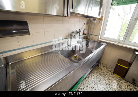 Grand évier de cuisine industriel en acier inoxydable avec robinet ouvert Banque D'Images