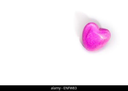 Un coeur de pierre rose couché sur fond blanc. Avec copyspace Banque D'Images