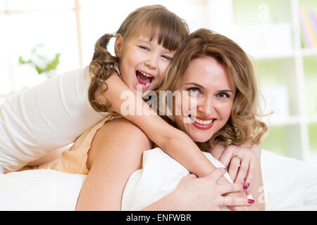 Femme d'âge moyen et kid girl in bed playing and smiling Banque D'Images