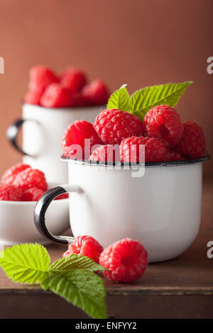 Tasses en émail framboise fraîche sur fond de bois Banque D'Images