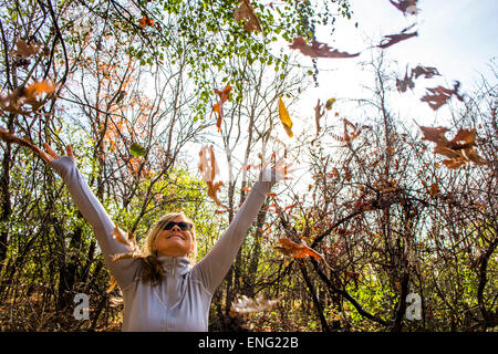 Caucasian woman throwing autumn leaves in forest Banque D'Images