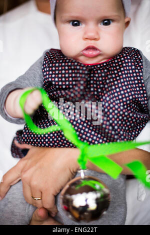 Close up of Caucasian baby girl holding Christmas ornament Banque D'Images