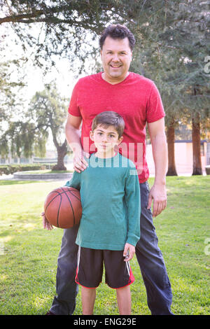 Caucasian father and son smiling in park with basketball Banque D'Images