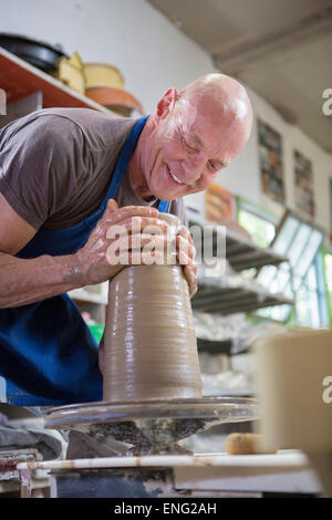 Older Caucasian man poterie formant sur roue en studio de céramique Banque D'Images