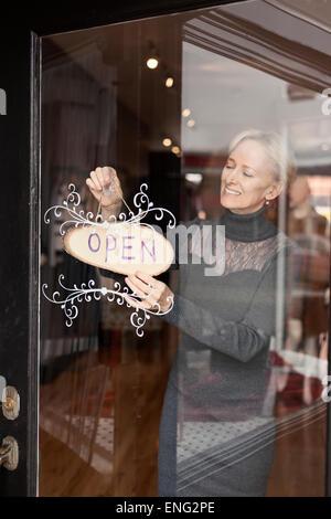 Portrait of small business owner hanging open sign sur porte avant Banque D'Images