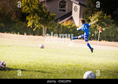 Mixed Race boy playing soccer sur terrain Banque D'Images