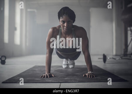 Black woman doing push-ups en salle de sport Banque D'Images