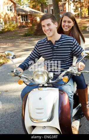 Couple riding scooter dans quartier de banlieue Banque D'Images