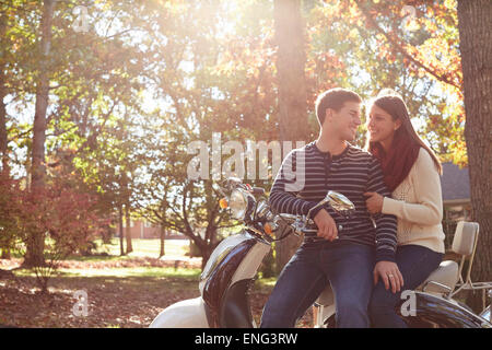 Couple sitting on scooter in park Banque D'Images