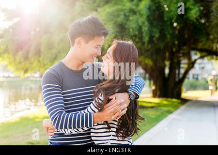 Smiling Korean couple hugging in park Banque D'Images