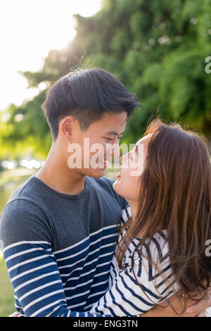 Smiling Korean couple hugging in park Banque D'Images