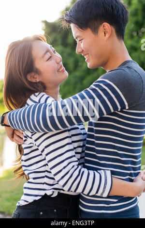 Smiling Korean couple hugging in park Banque D'Images