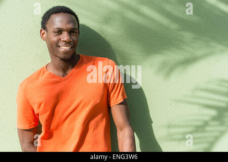 Black man standing under palm tree shadow on wall Banque D'Images