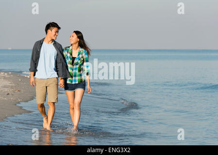 Balades en couple coréen dans les vagues sur la plage Banque D'Images