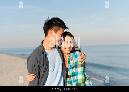 Smiling Korean couple hugging on beach Banque D'Images