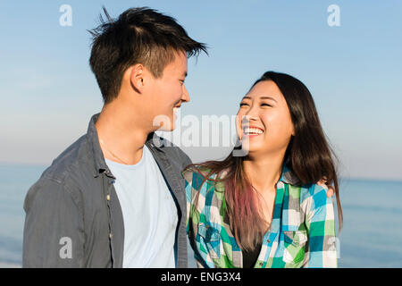 Smiling Korean couple hugging on beach Banque D'Images