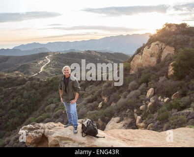 Caucasian homme debout sur une colline rocheuse Banque D'Images