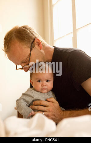 Father kissing baby boy on bed Banque D'Images