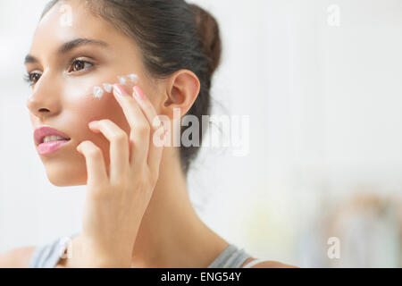 Woman applying moisturizer de joue Banque D'Images