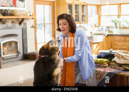 Hispanic woman petting dog in kitchen Banque D'Images