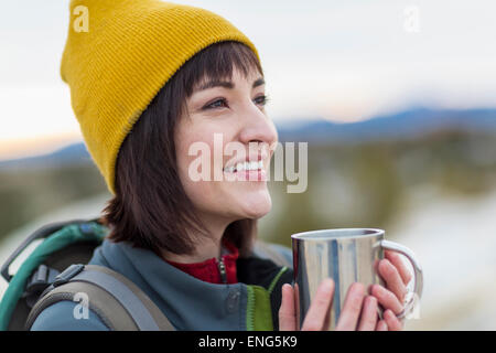 Hispanic woman drinking coffee outdoors Banque D'Images