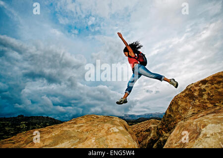 Hispanic woman jumping crevasse sur rock formation Banque D'Images