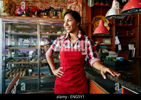 Hispanic waitress smiling in bakery Banque D'Images