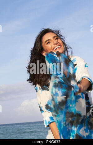 Hispanic woman playing avec tissu bleu on beach Banque D'Images