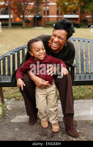 African American mother and son playing on park bench Banque D'Images