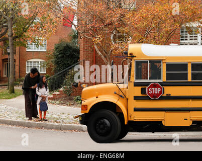 African American Woman waiting avec fille pour les autobus scolaires Banque D'Images