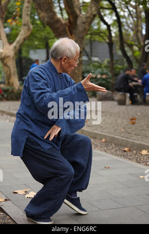 Homme mature pratiquant le taiji quan (ou taichi) dans un parc du centre-ville ; Parc de Renmin, Shanghai, Chine. Banque D'Images