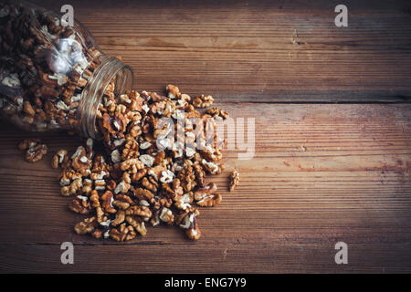 Les cerneaux de noix et les noix entières sur table en bois rustique vieux pot en verre Banque D'Images