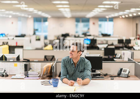 Un jeune homme assis à un bureau dans un bureau. Banque D'Images