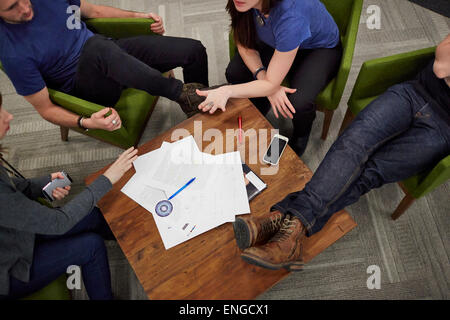 Vue aérienne d'une réunion de quatre personnes assises autour d'une table basse. Banque D'Images