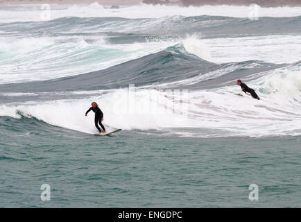 L'ANSE DE SENNEN, Cornwall, Angleterre - 22 octobre 2014 : Surfers attraper une vague lors d'une froide journée d'automne, le 22 octobre 2014 dans Sennen Co Banque D'Images