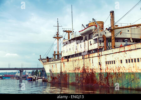 Vieux bateau rouillé abandonné est amarré dans le port de Varna, Bulgarie. Vintage photo stylisée avec filtre de correction tonale Banque D'Images