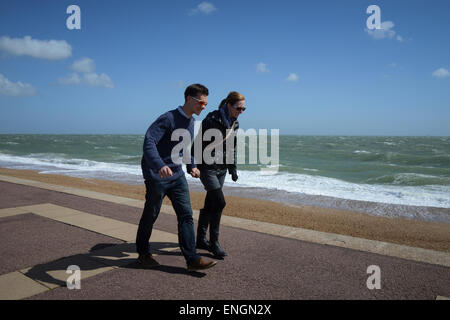 Quelques holds​ mains comme ils ont du mal à marcher le long de la promenade de Southsea à Portsmouth, Hampshire, Angleterre par un jour de vent. Banque D'Images