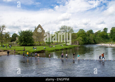 Les touristes et les visiteurs qui traversent le tremplin en face de Saint-cergue prieuré. Bolton Abbey, Wharfedale, Royaume-Uni. Banque D'Images