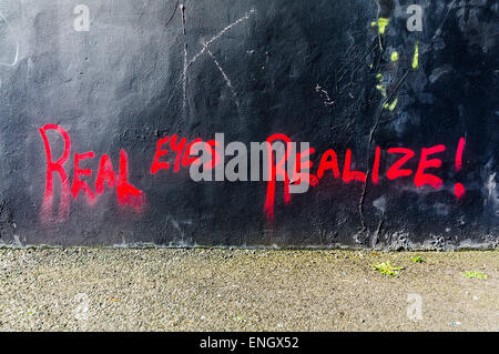 Graffiti sur un mur en disant 'Vrais yeux. réaliser !' Banque D'Images