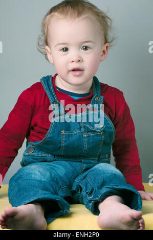 Portrait of smiling un an baby boy in red top et salopette Banque D'Images