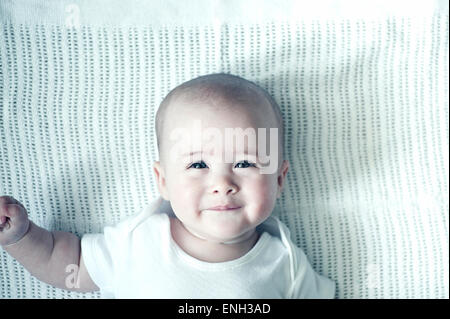 Cute Caucasian baby portant sur la couverture blanche Banque D'Images