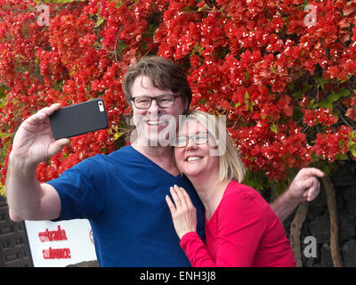 « SELFIE » couple séduisant s'amuser en vacances prendre une photo « selfie » en dehors de l'attraction de vacances sur leur application d'appareil photo iPhone Banque D'Images