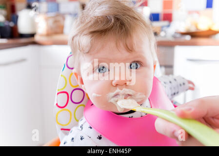 À l'âge de six mois, l'alimentation à la cuillère bébé fille sur le porridge Banque D'Images