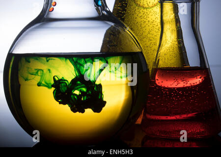 Réaction chimique avec éclairage arrière spectaculaire. Produits chimiques jaune et orange, vert la fumée chimique. Banque D'Images