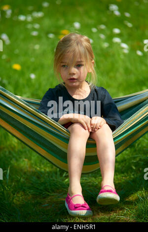 Portrait de petit enfant fille blonde allongé et se reposant dans un hamac, cour, jardin de l'été Banque D'Images