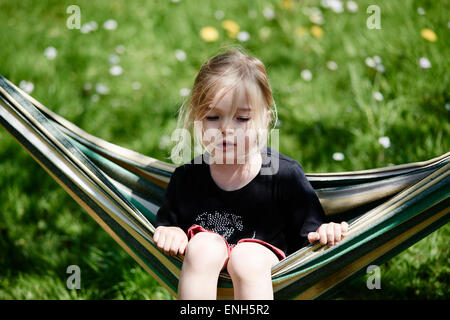 Portrait de petit enfant fille blonde allongé et se reposant dans un hamac, cour, jardin de l'été Banque D'Images