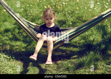 Portrait de petit enfant fille blonde allongé et se reposant dans un hamac, cour, jardin de l'été Banque D'Images