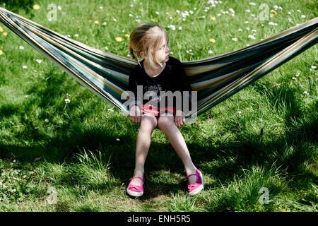 Portrait de petit enfant fille blonde allongé et se reposant dans un hamac, cour, jardin de l'été Banque D'Images