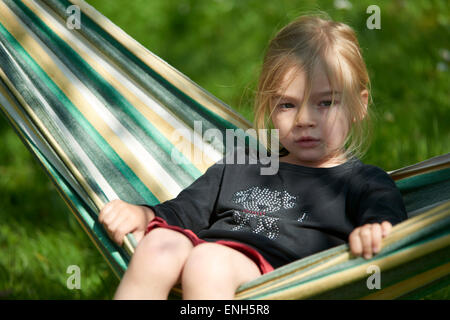 Portrait de petit enfant fille blonde allongé et se reposant dans un hamac, cour, jardin de l'été Banque D'Images